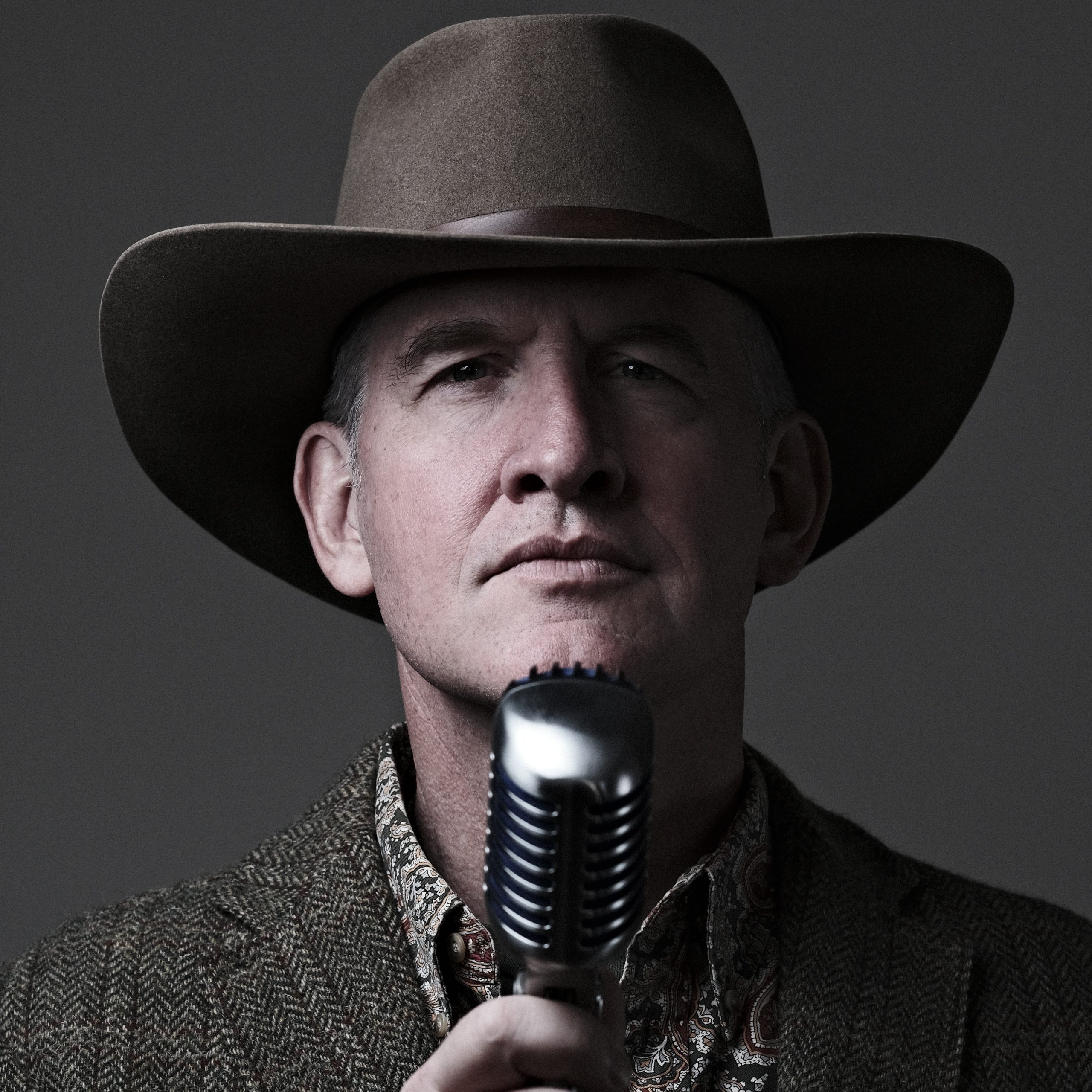 Self portrait of Michael Scherer wearing wide-brimmed hat in front of a chrome microphone.